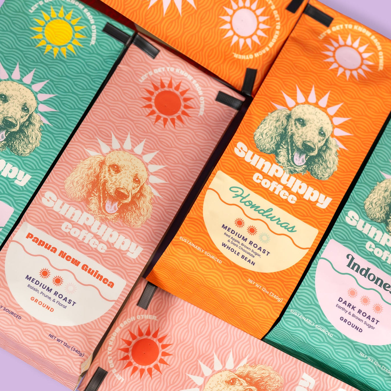 Sunpuppy Coffee collection featuring Papua New Guinea Honduras and Indonesia varieties in pink orange and teal packaging with standard poodle mascot medium and dark roast whole bean coffee
