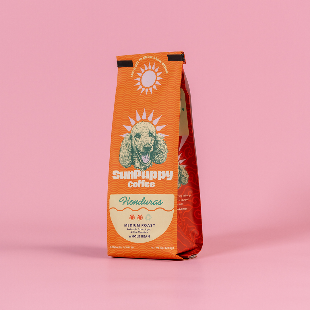 Sunpuppy Coffee Honduran medium roast whole bean coffee in orange packaging featuring golden retriever mascot with sun logo on pink background 12 ounces